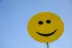 a yellow smiley face sign with a blue sky in the background